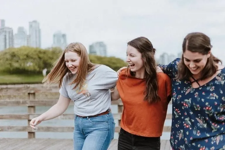 Three woman laughing to the backdrop of a city